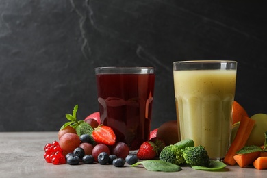 Photo of Delicious juices and fresh ingredients on grey table against black background