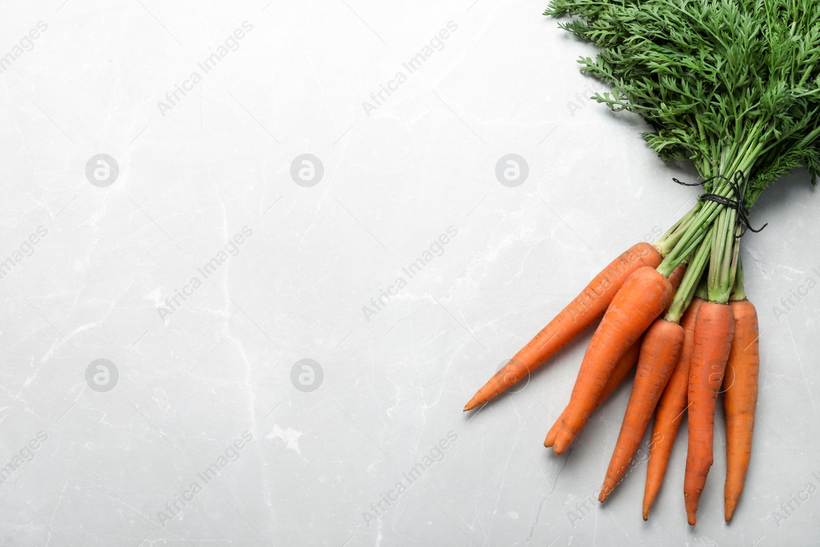 Photo of Ripe carrots on light grey marble table, flat lay. Space for text