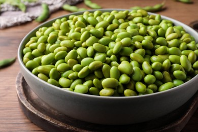 Photo of Bowl of delicious edamame beans on wooden table, closeup