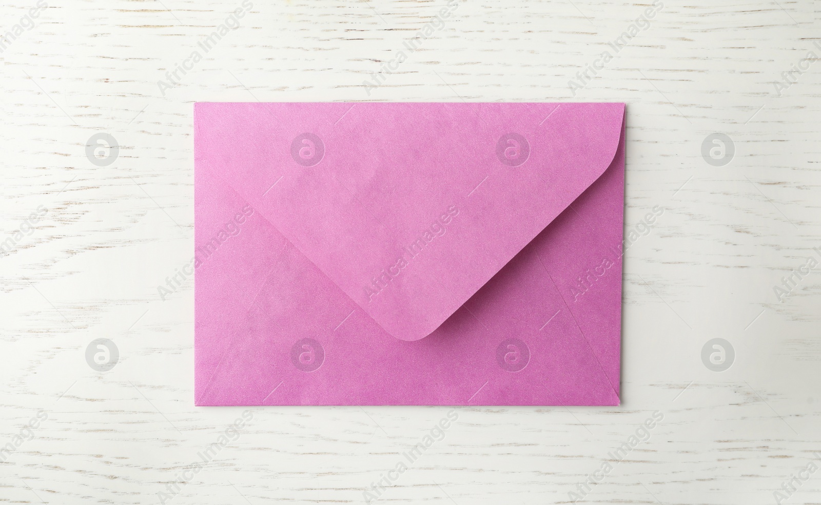 Photo of Pink paper envelope on white wooden background, top view