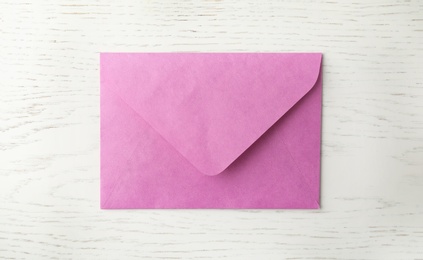 Photo of Pink paper envelope on white wooden background, top view