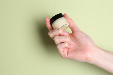 Photo of Woman holding jar of cream on green background, closeup. Space for text