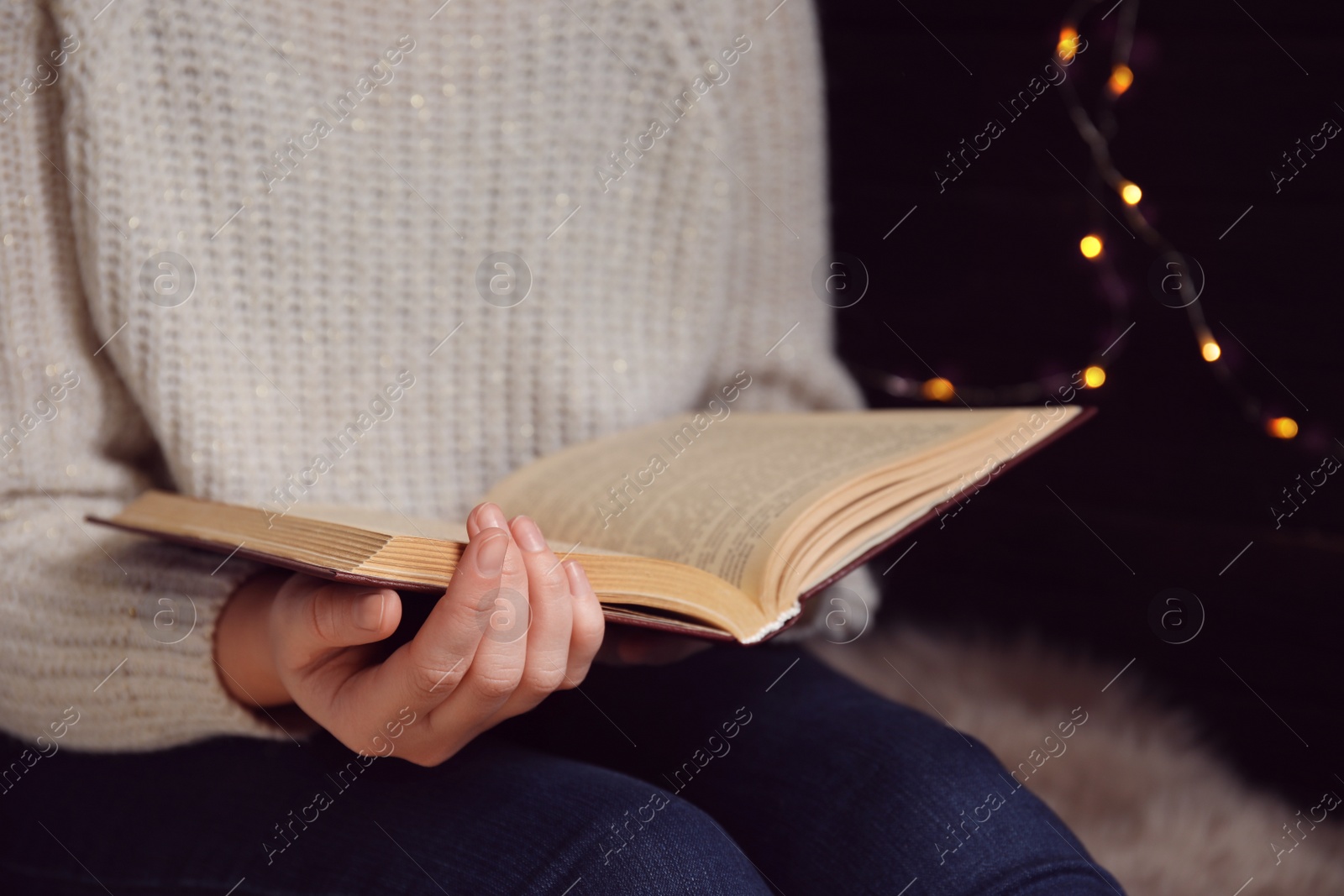 Photo of Young woman reading book at home, closeup