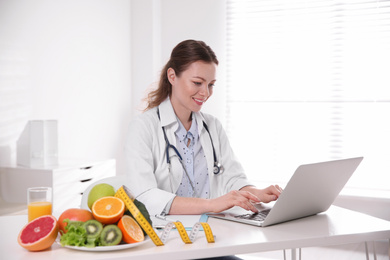 Photo of Nutritionist working with laptop at desk in office