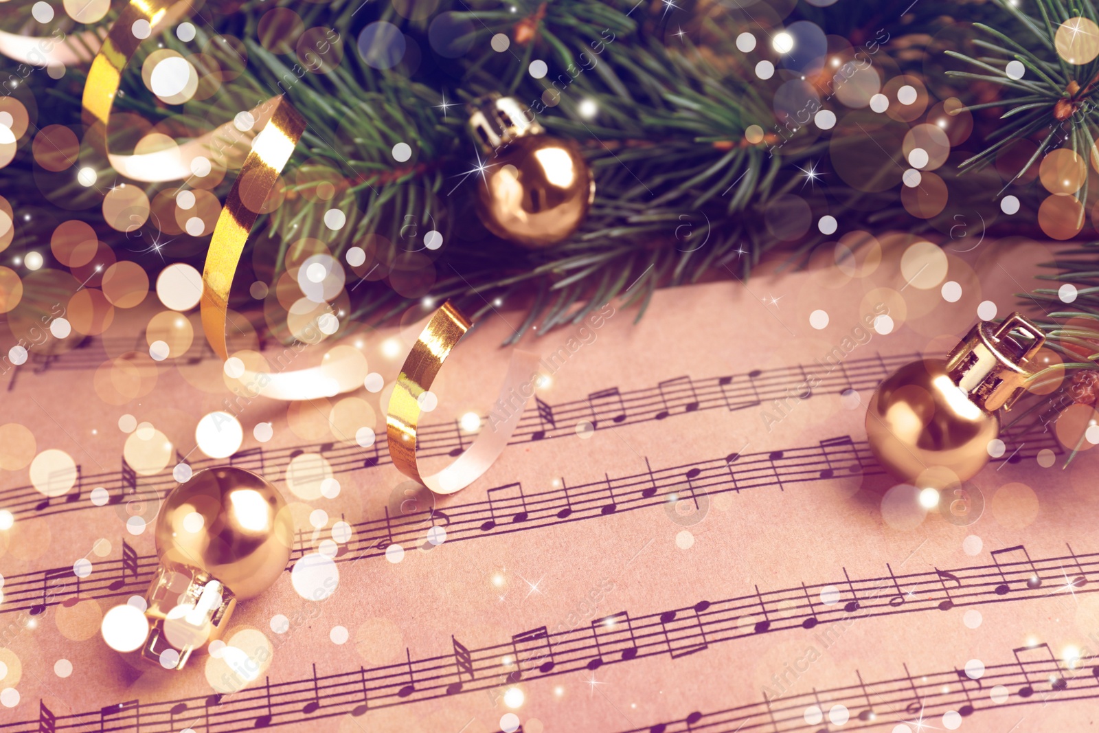 Image of Fir branches and golden balls on Christmas music sheets, above view. Bokeh effect