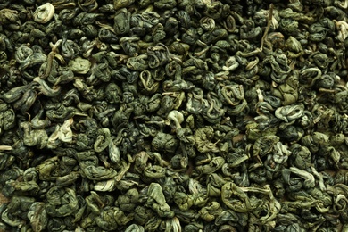 Photo of Dry green tea leaves as background, top view