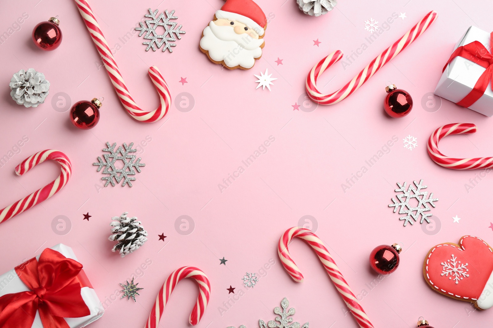 Photo of Frame of candy canes and Christmas decor on pink background, flat lay. Space for text