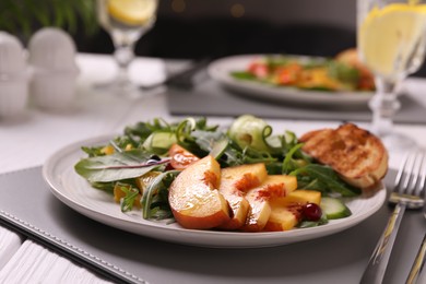 Photo of Delicious salad with peach slices served on table, closeup