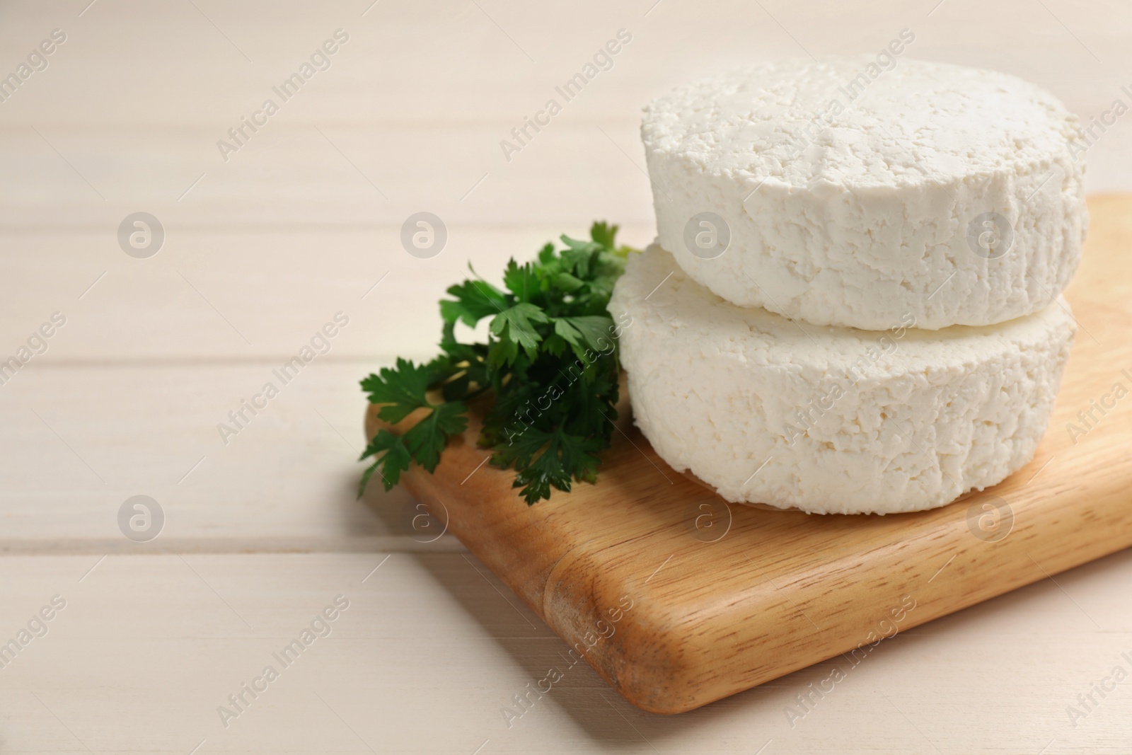 Photo of Delicious fresh cottage cheese with parsley on white wooden table, closeup. Space for text