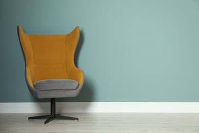 Comfortable armchair against color wall