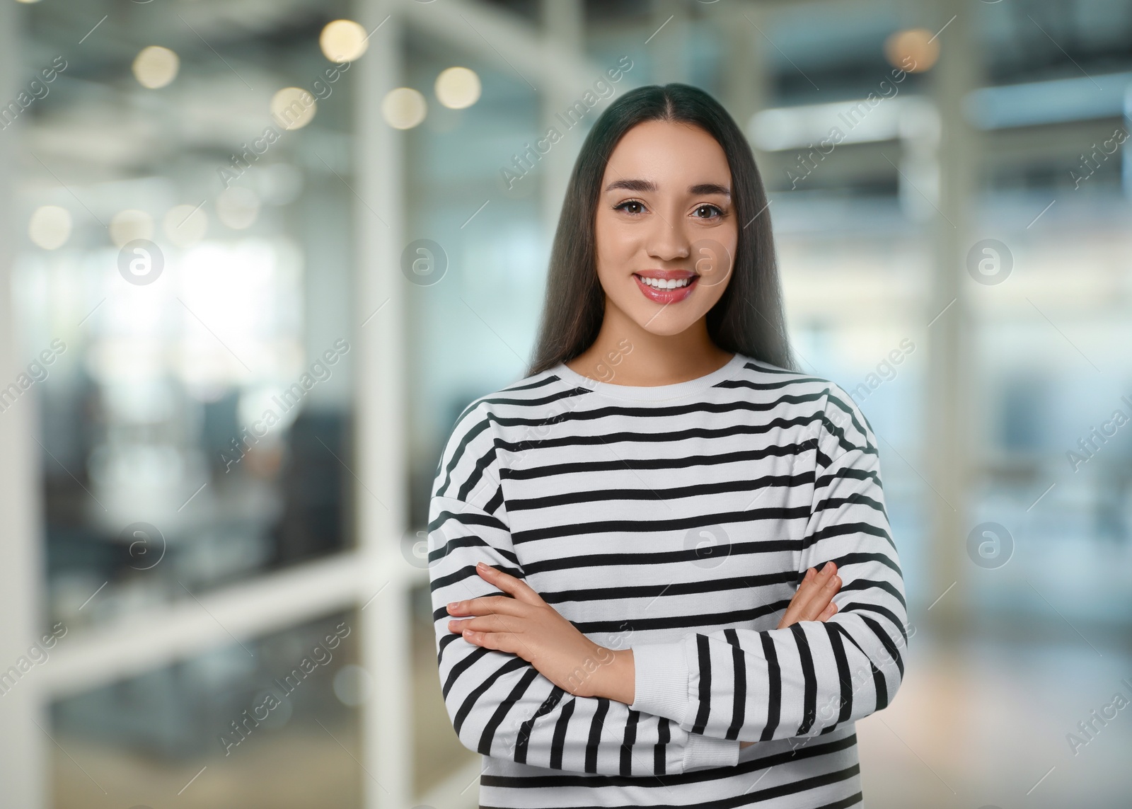 Image of Portrait of happy woman in office. Pretty girl looking at camera and smiling on blurred background