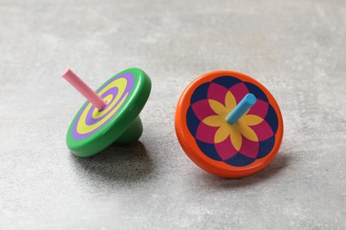 Photo of Bright spinning tops on grey textured background, closeup