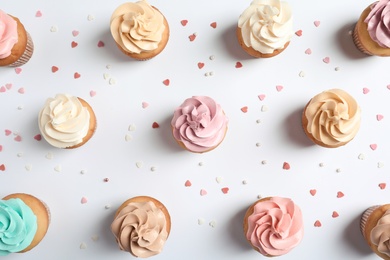 Photo of Flat lay composition with delicious birthday cupcakes on white background