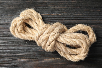 Bundle of natural hemp rope on wooden background, closeup