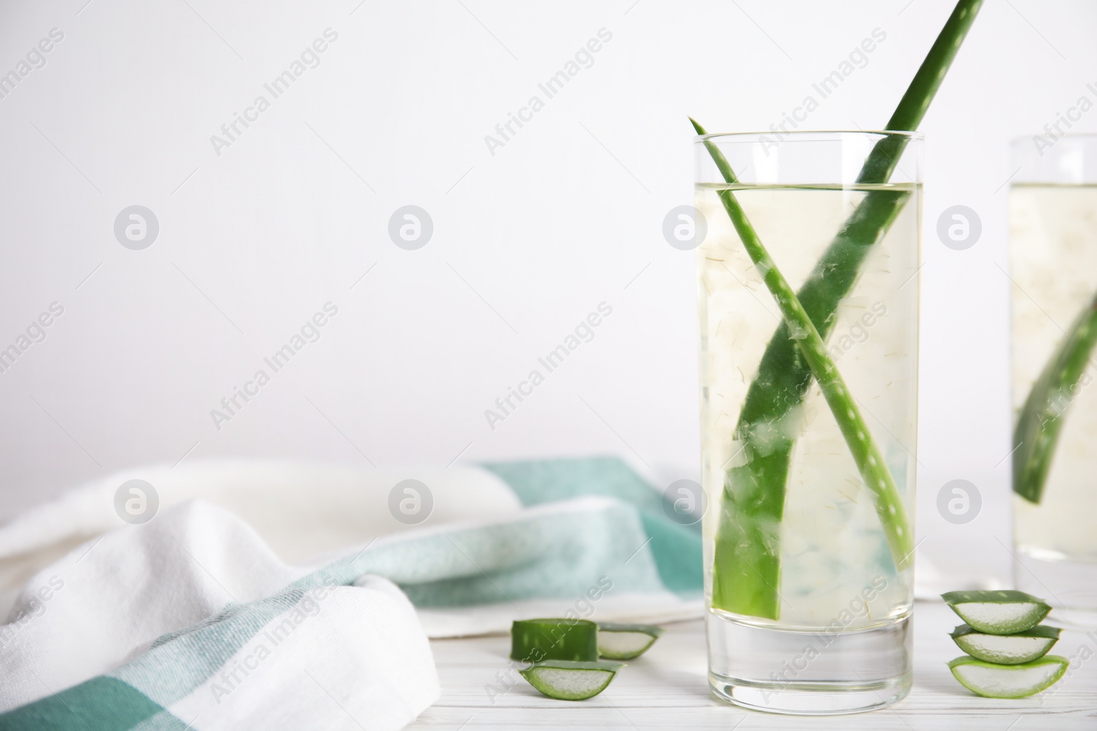 Photo of Fresh aloe drink with leaves in glasses on white wooden table. Space for text