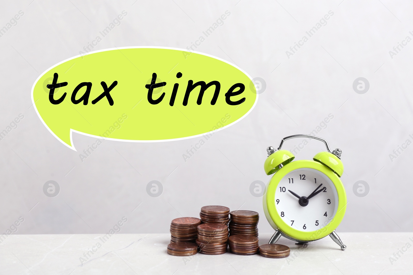 Image of Time to pay taxes. Alarm clock and stacked coins on table