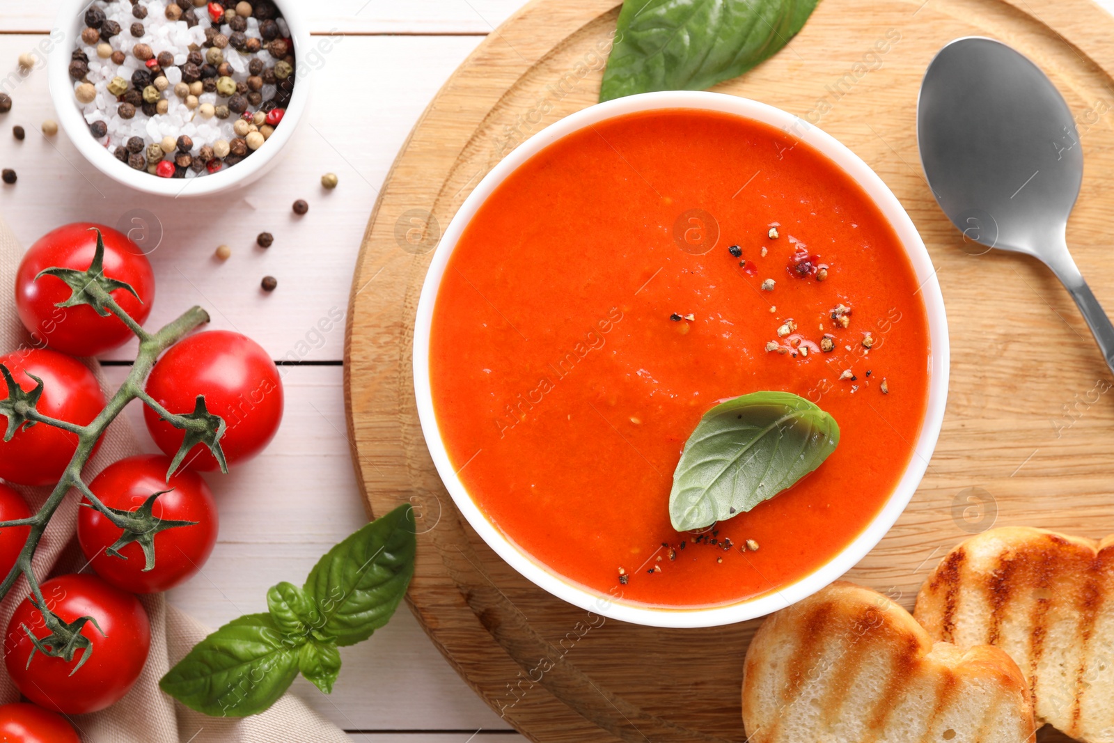 Photo of Delicious tomato soup served on white wooden table, flat lay