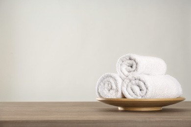 Photo of Fresh rolled towels on wooden table. Space for text