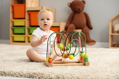 Photo of Children toys. Cute little boy playing with bead maze on rug at home