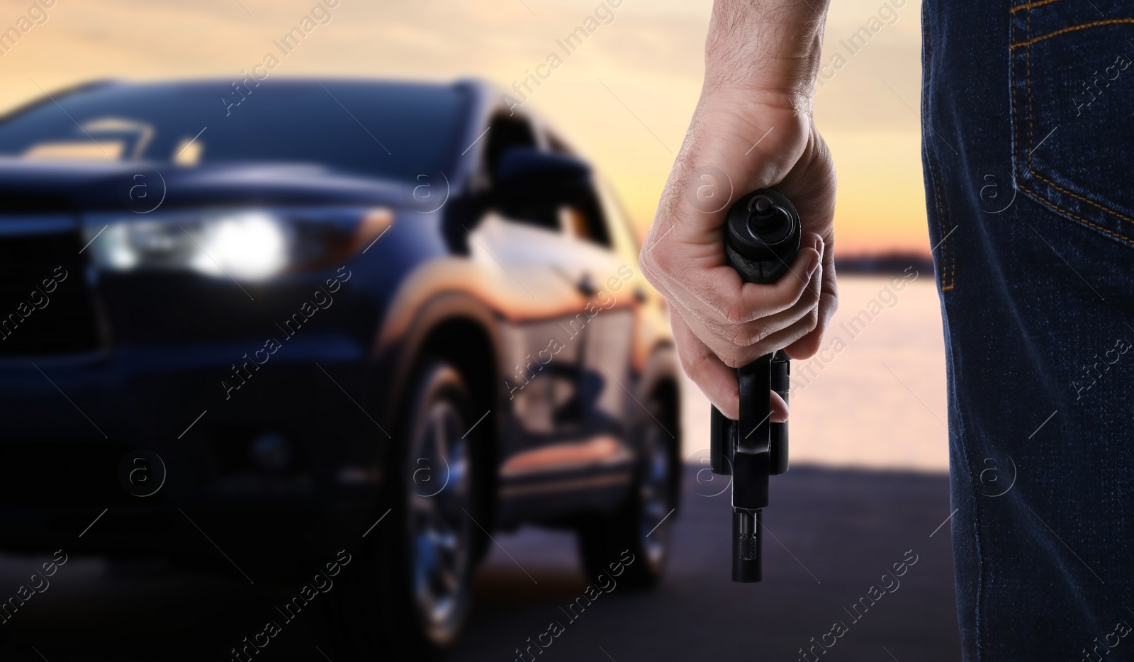 Image of Man with gun near luxury car outdoors, closeup
