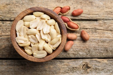 Photo of Fresh peanuts in bowl on wooden table, top view