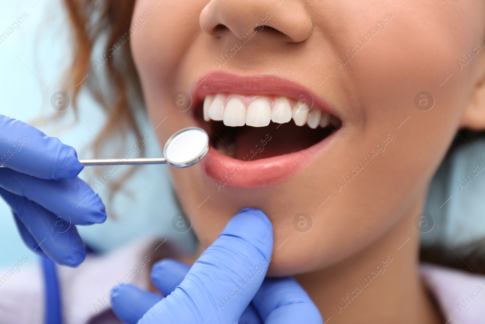 Photo of Dentist examining African-American woman's teeth with mirror, closeup