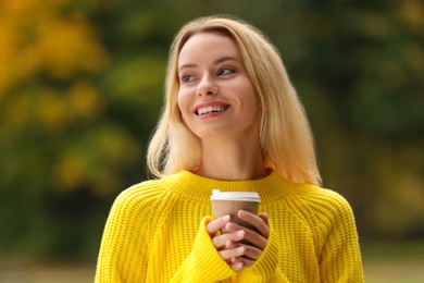 Autumn vibes. Portrait of happy woman with paper cup outdoors