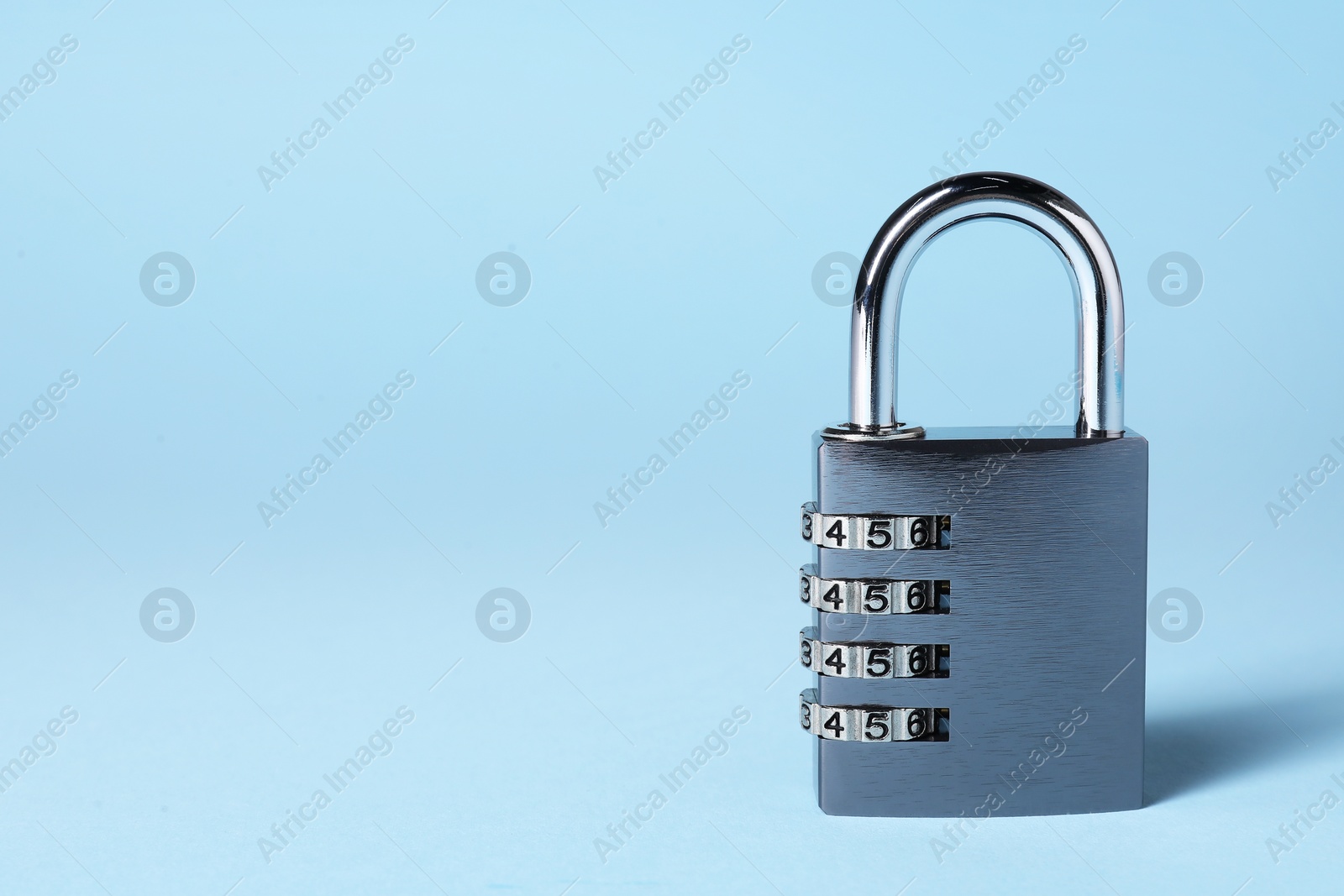 Photo of Steel combination padlock on light blue background. Space for text