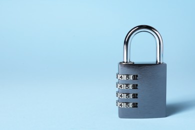 Steel combination padlock on light blue background. Space for text