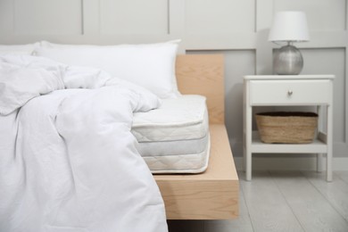 Photo of Wooden bed with soft white mattress, blanket and pillows indoors