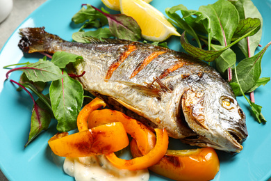 Photo of Delicious roasted fish with lemon and vegetables on plate, closeup