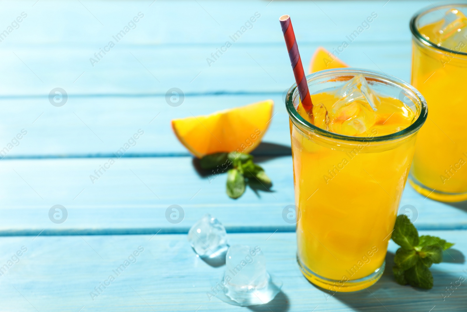 Photo of Delicious orange soda water on light blue wooden table. Space for text