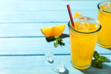 Delicious orange soda water on light blue wooden table. Space for text