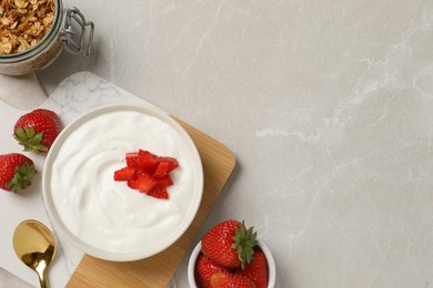 Yogurt served with strawberries on grey marble table, flat lay. Space for text