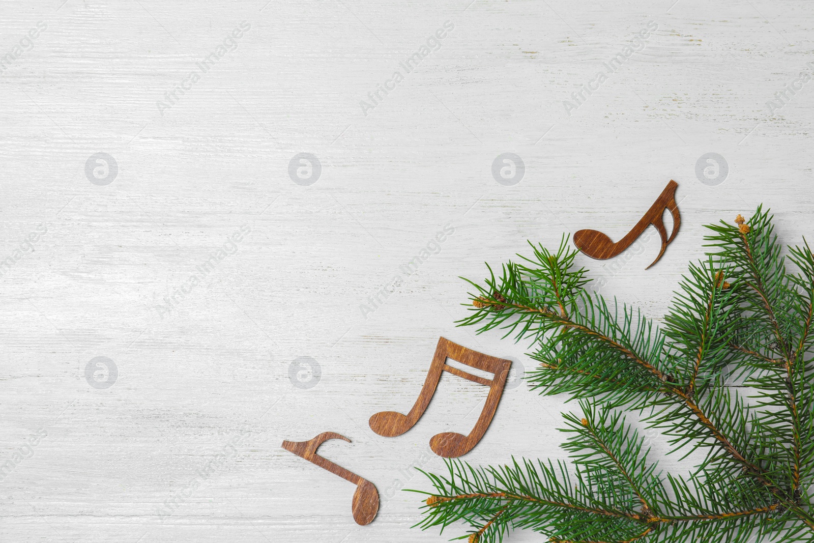 Photo of Flat lay composition with Christmas tree branch, music notes and space for text on white wooden background
