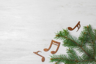 Flat lay composition with Christmas tree branch, music notes and space for text on white wooden background