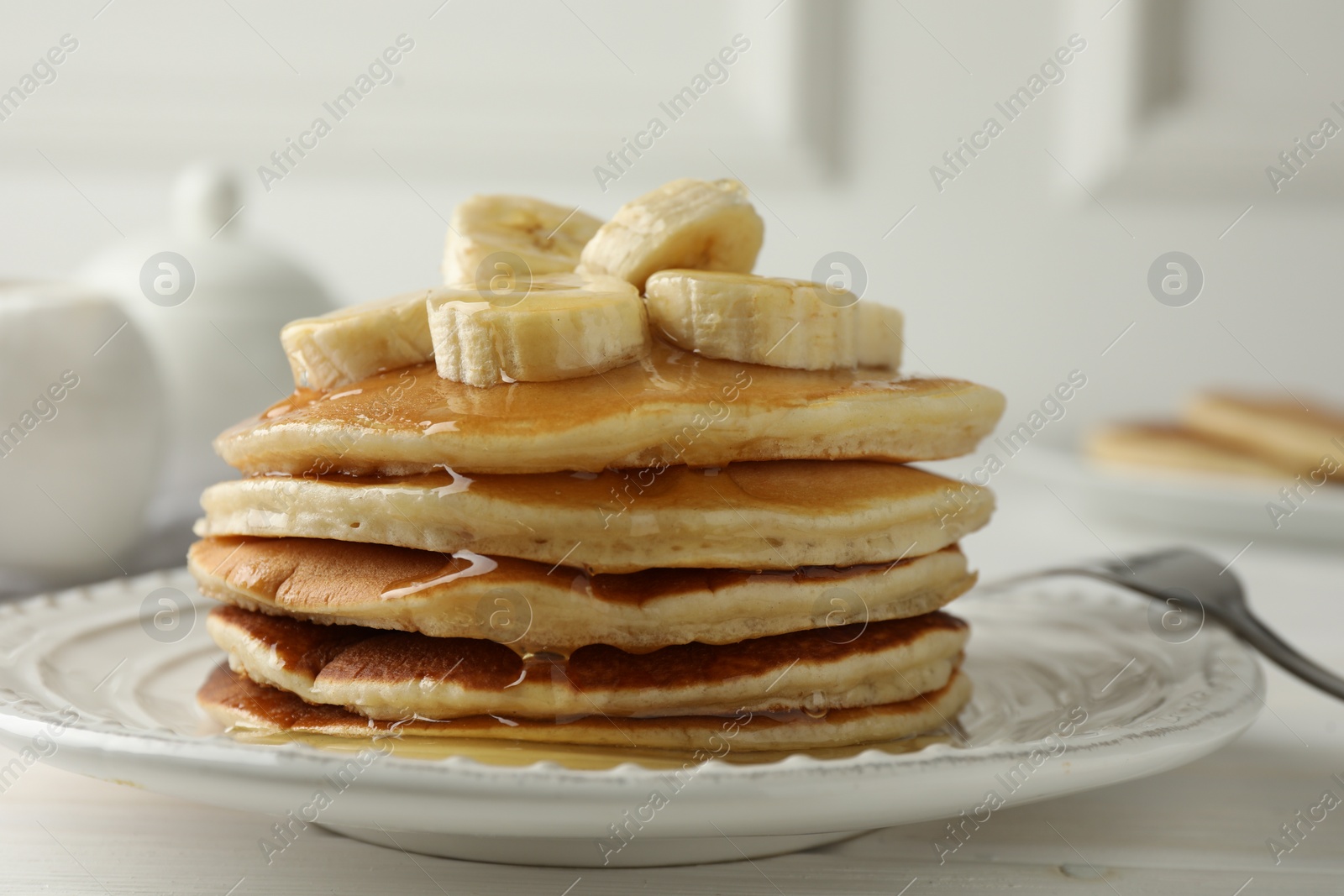 Photo of Delicious pancakes with bananas and honey on white wooden table, closeup