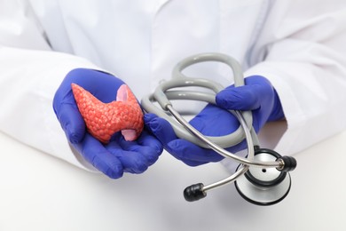 Photo of Endocrinologist holding stethoscope and model of thyroid gland, closeup