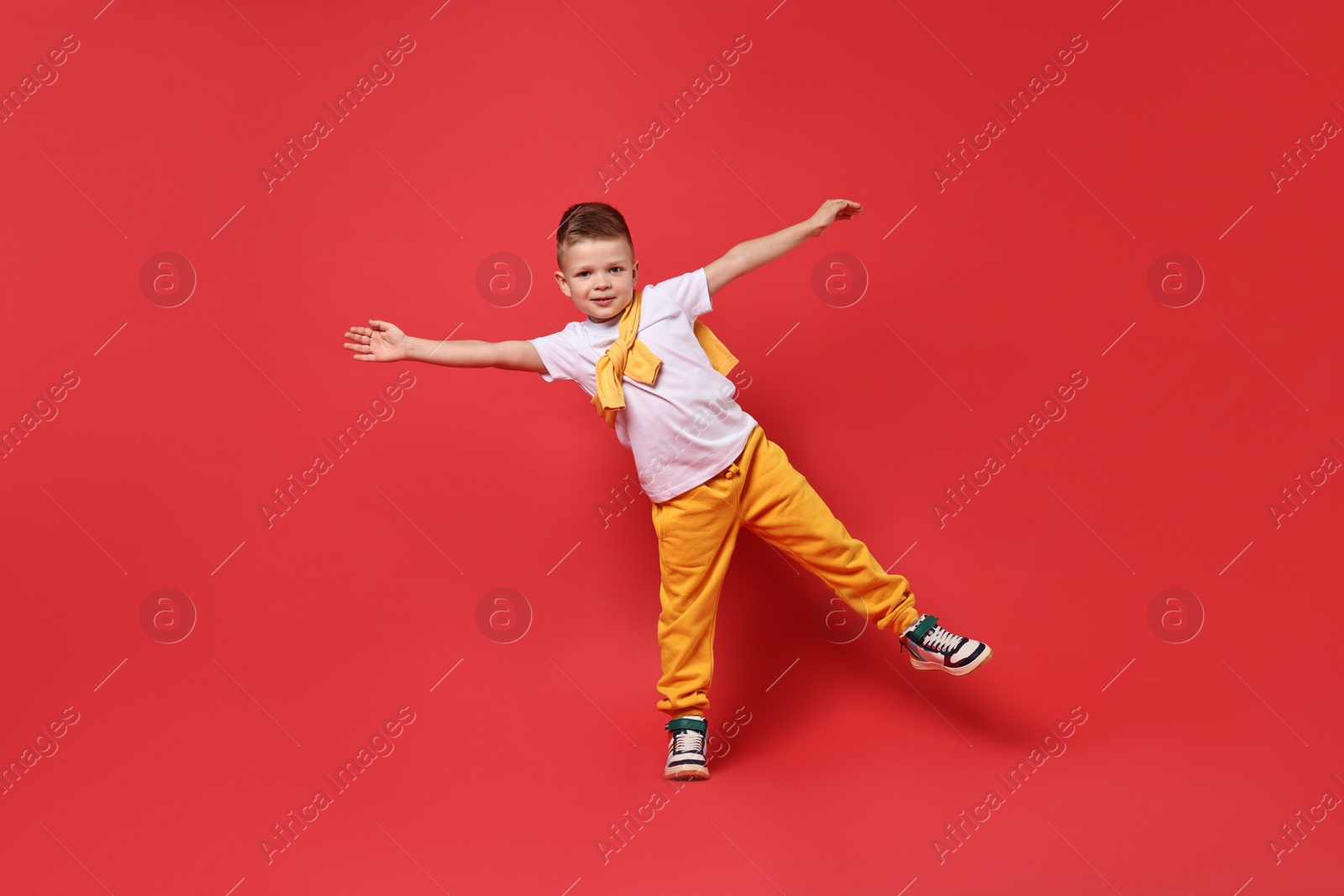 Photo of Happy little boy dancing on red background