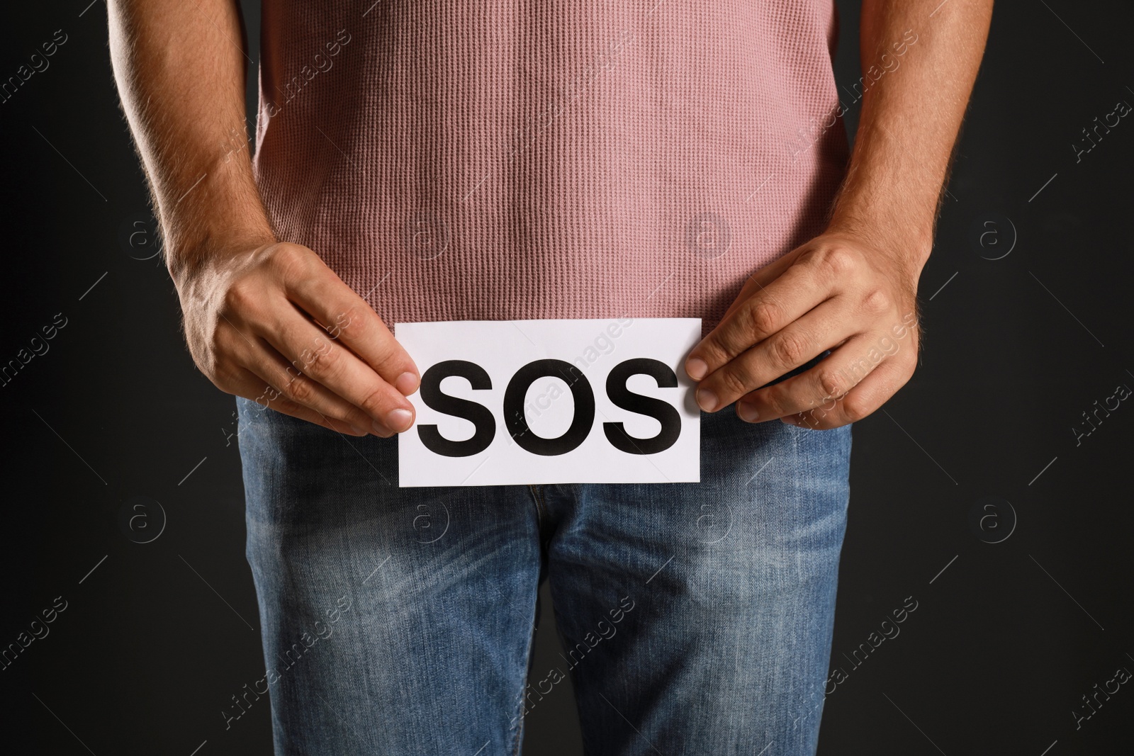 Photo of Man holding SOS sign on black background, closeup. Urology problems