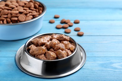 Wet and dry pet food on light blue wooden table, space for text