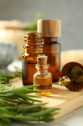 Essential oils in bottles and rosemary on table, closeup