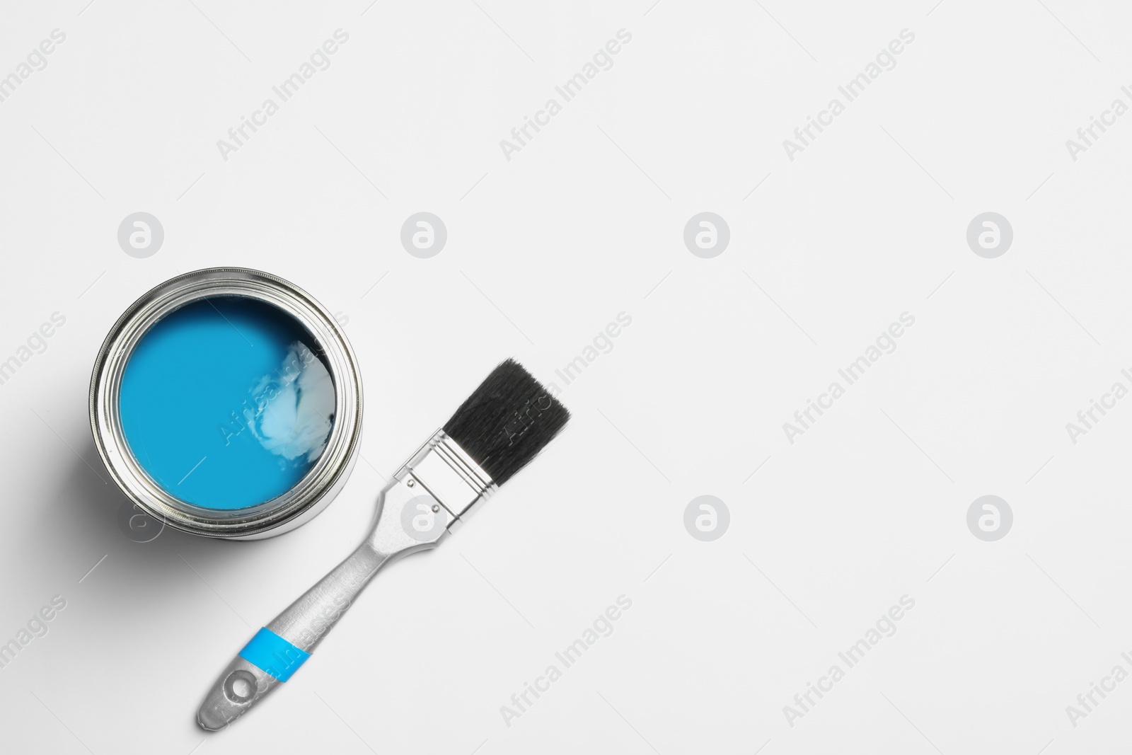 Photo of Paint can and brush on white background, top view. Space for text
