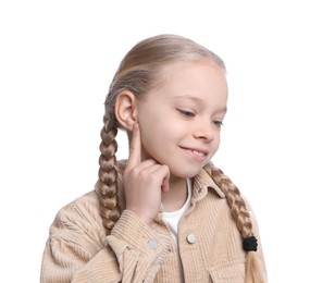 Photo of Cute little girl pointing at her ear on white background