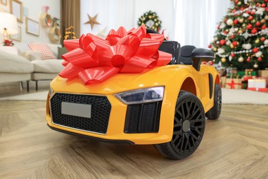 Photo of Children's electric toy car with red bow in room decorated for Christmas