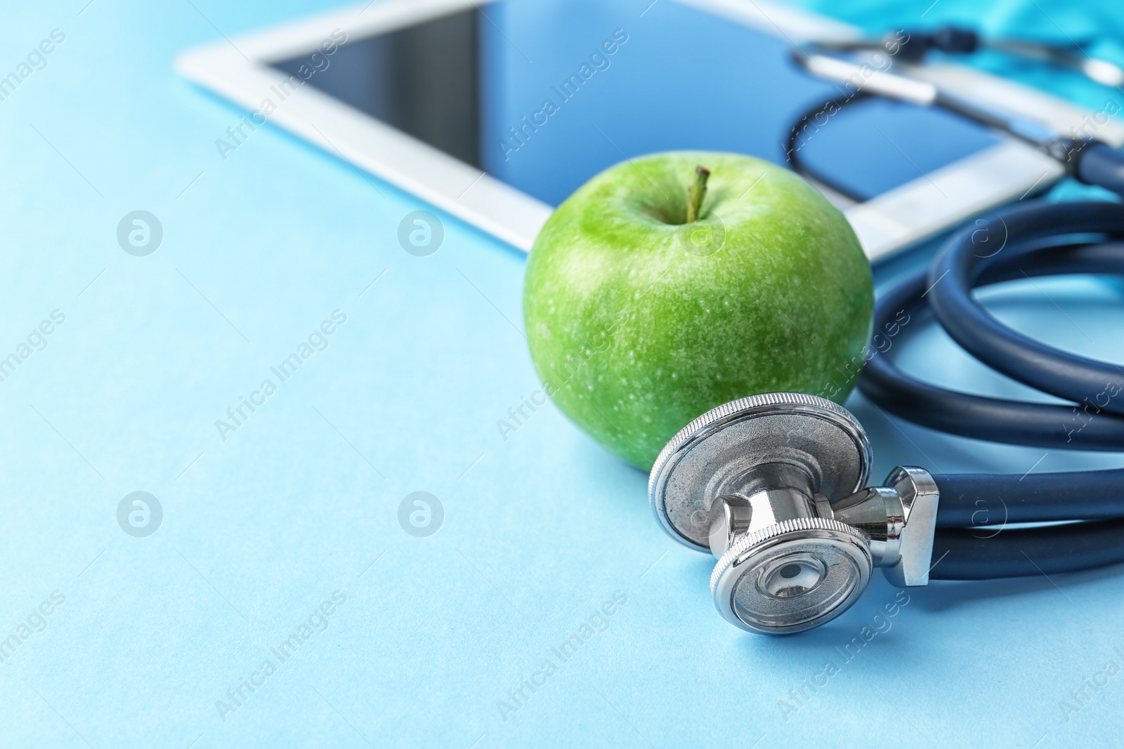 Photo of Stethoscope and apple on color background. Medical equipment