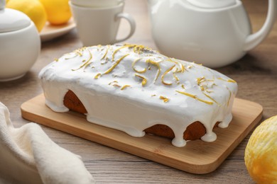 Photo of Tasty lemon cake with glaze on wooden table
