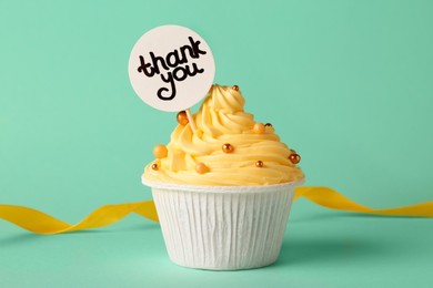 Photo of Tasty cupcake and note with phrase Thank You on turquoise background