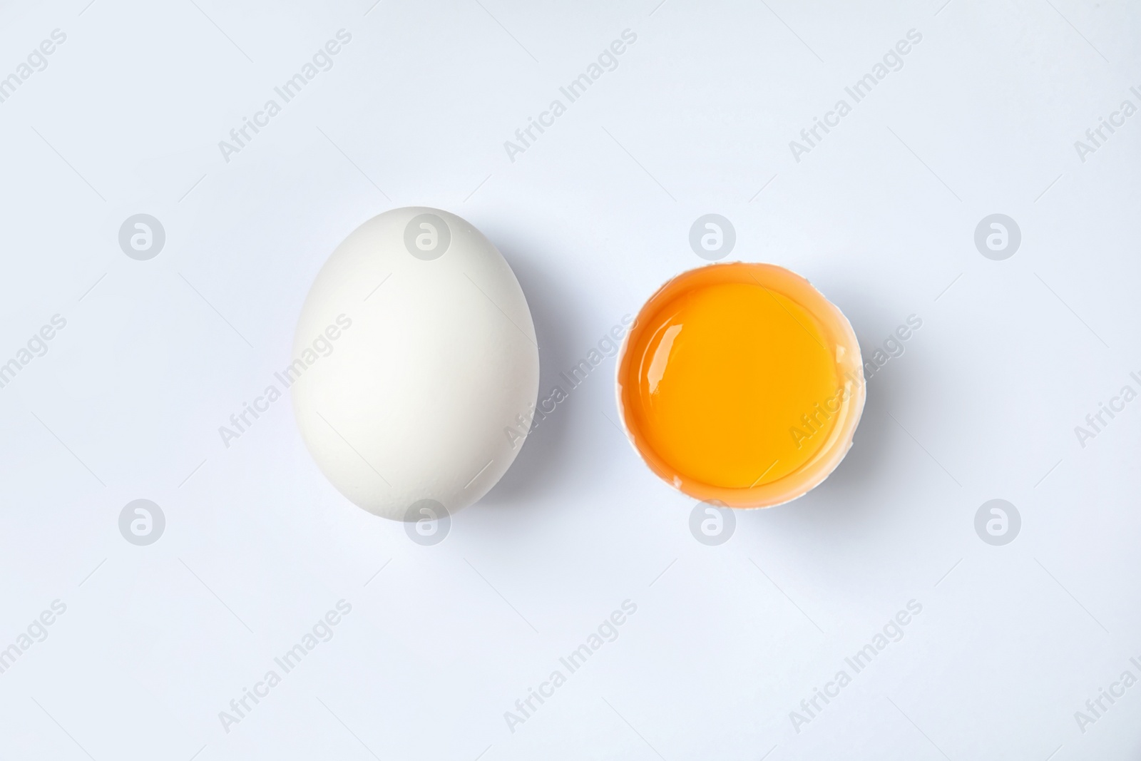 Photo of Raw chicken eggs with yolk on white background, top view