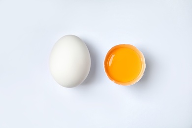 Photo of Raw chicken eggs with yolk on white background, top view